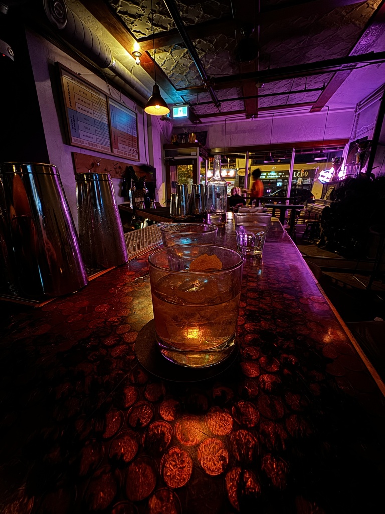 A photo in a dimly-lit bar, with several drinks on a table. 